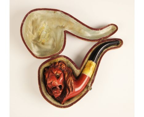 A carved 'meerschaum' style pipe, 19th century, the pipe mounted with a carved head of a lion with glass inset eyes, stained 