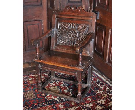 * A 17th century oak Wainscot chair, the shaped top rail with three roundels over a back panel carved with flowerhead and lea