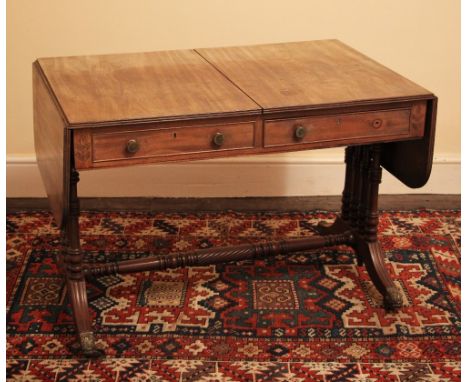 * A Regency mahogany sofa table, the drop leaf top with a reeded edge over alternating frieze drawers, opposed by faux drawer