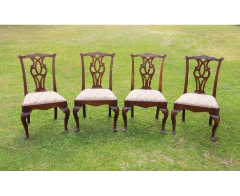 * A set of four George II mahogany dining chairs, each chair with a cupids bow top rail extending to scroll terminals, over t