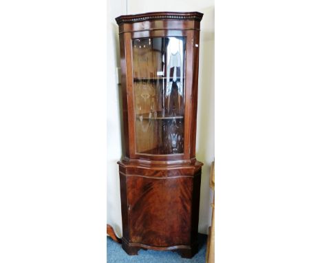 A bow fronted glazed freestanding corner cabinet