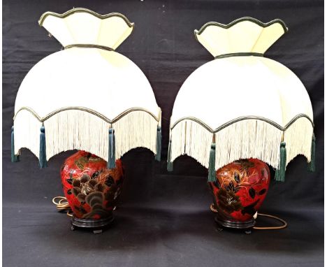 PAIR OF CERAMIC TABLE LAMPSwith gilt decorated black birds and flowers on a mottled red ground, raised on wooden stands and w