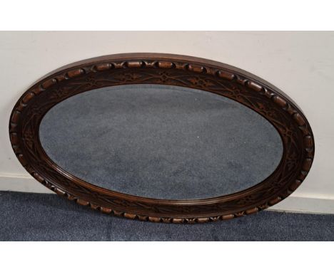 LARGE OAK OVAL WALL MIRRORwith bevel edge, the frame with decorative fret patterns, 113 x 77cm