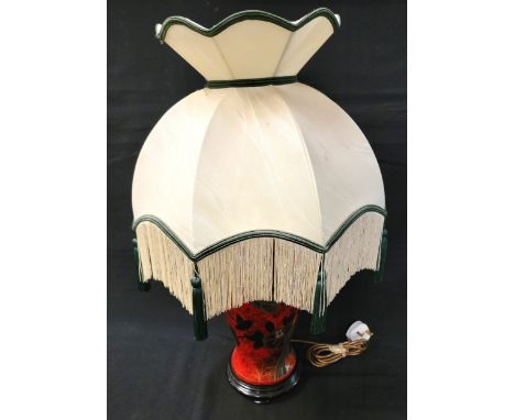 CERAMIC TABLE LAMPwith gilt decorated black birds and flowers on a mottled red ground, raised on wooden stand and with fringe
