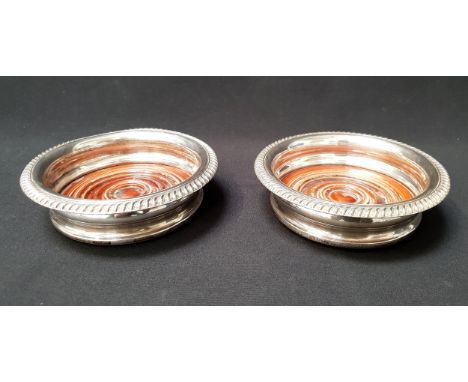 PAIR OF GEORGE V SILVER MOUNTED WINE COASTERSBirmingham 1935, with gadrooned edges on  turned Mahogany bases, 14.5cm diameter