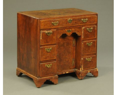 An 18th century burr walnut kneehole desk, with caddy top above a series of frieze drawers and cupboard and all raised on bra