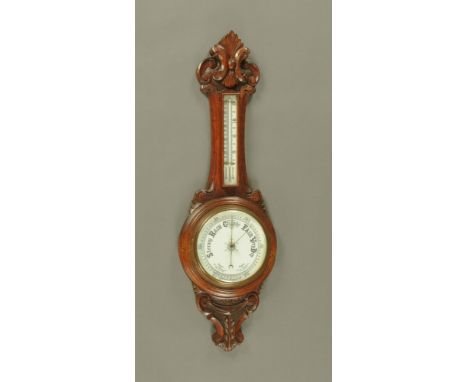 A carved oak cased aneroid barometer with mercury thermometer.  Height 87 cm.
