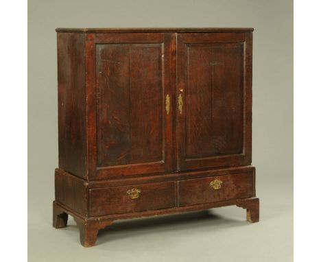 An 18th century oak cupboard on stand, with raised and fielded panel construction with two base drawers.  Height 130 cm, widt