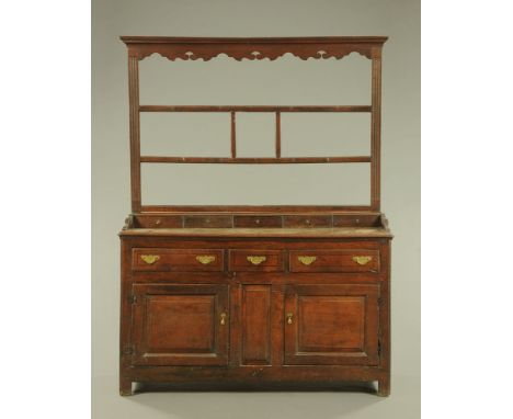 A George III oak dresser with Delft rack, the base fitted with spice drawers, drawers and cupboards and raised on stile feet.