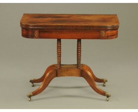 A Regency brass inlaid rosewood turnover top card table, with rounded corners, bobbin turned supports and quatreform base wit