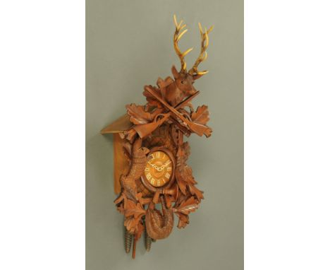 A Black Forest style cuckoo clock, with typical carved case, with hunting emblems.  Overall height +/- 80 cm, width 43 cm, de