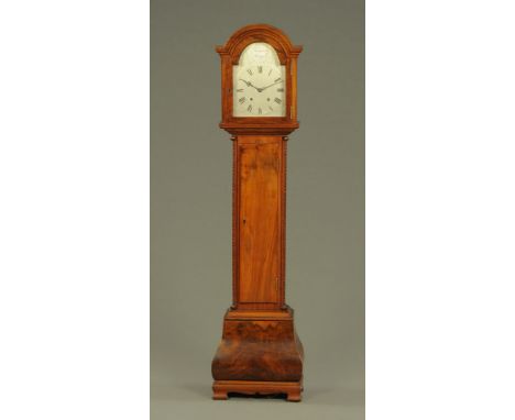 A walnut cased grandmother clock, with two train striking movement and silvered dial, with long trunk door and Bombe base rai