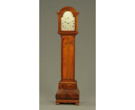 A walnut cased grandmother clock, with two train striking movement and silvered dial, with long trunk door and Bombe base rai