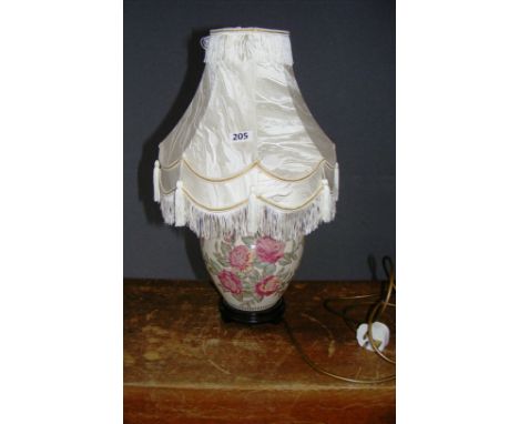 A porcelain table lamp decorated with flowers, with an ornate shade.