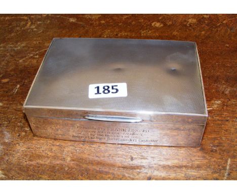 A sterling silver cigarette box, engine turned and with an inscription to the front, assayed Birmingham 1935.