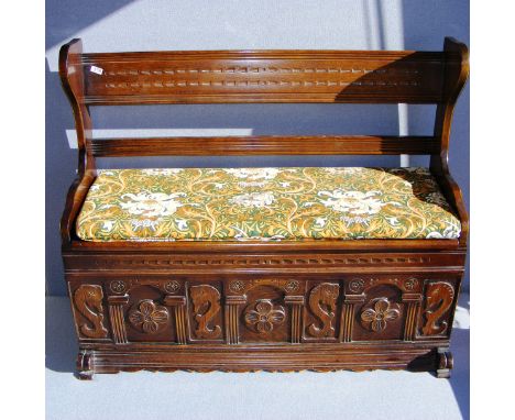 A mid 20th century solid oak monks bench, ornately carved to the front with sea horses and flowers.