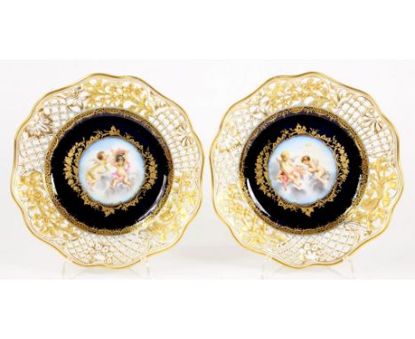 A PAIR OF CONTINENTAL PORCELAIN RETICULATED COBALT GROUND CABINET PLATES, PAINTED TO THE CENTRE WITH PUTTI ON CLOUDS AND RICH