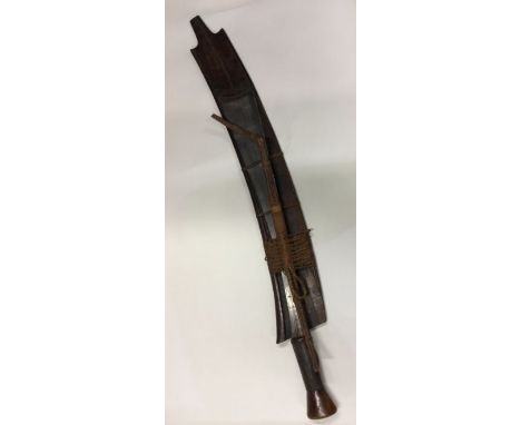 A tribal steel bladed knife in carved scabbard. Est. £30 - £40.