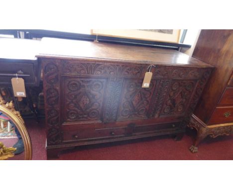 A mid 17th century oak coffer, with three deeply carved floral panels, having marquetry inlay, above two faux drawers, raised