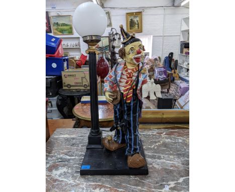 A large painted fibreglass table lamp fashioned as a clown next to a street lampLocation: 