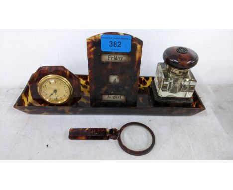 A collection of early 20th century tortoiseshell desk items to include a calendar, clock inkwell with a silver collar and an 