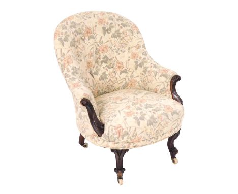 A Victorian mahogany spoon back armchair, upholstered in floral cream button back fabric, raised on cabriole legs, brass capp