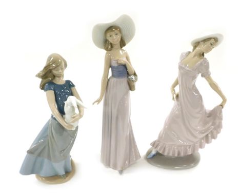 Three Nao porcelain figures of young ladies, one in a pink dress, another holding a rabbit, the third with a basket of flower