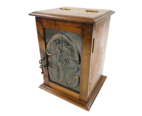 A Victorian Art Nouveau oak and copper panelled smoker's cabinet, with a hinged top and door embossed with stylized flowers, 