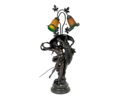 A bronzed plaster figural table lamp, modelled as Zephyr and Psyche, with two frosted orange to green frilled glass shades, 9