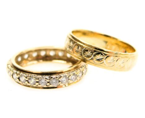 A 9ct gold wedding band, with engraved medallion decoration, 3.10g and a 9ct gold eternity ring set  with white stones (all r