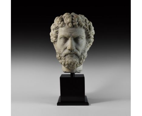 2nd century AD. The head of Emperor Antoninus Pius captured in marble; the stern features framed by a full head of curly tous