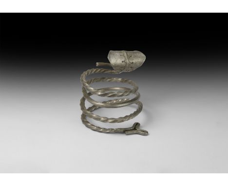 10th-12th century AD. A silver coiled arm-ring, round in section with alternating twisted and plain segments, Y-shaped finial