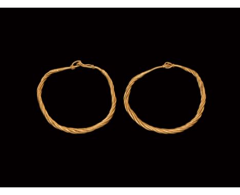 10th-11th century AD. A matched pair of gold bracelets each formed of twisted rods narrowing to each end with hook-and-eye fa