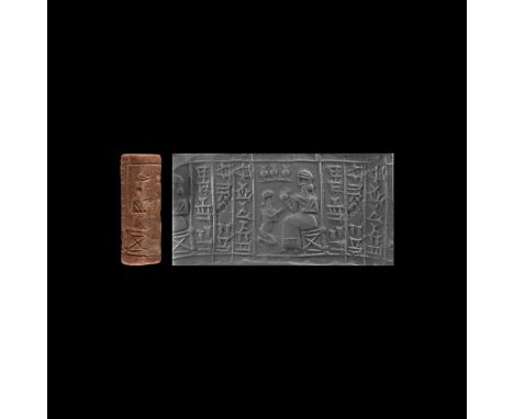 1500-1155 BC. A mottled limestone cylinder seal with a bearded god is facing left on a seat with a diagonal cross brace (very