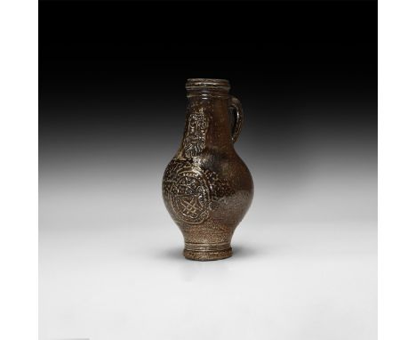 16th century AD. A mottled salt-glazed stoneware jug of bartmannskrug type with bulbous body, narrow tiered base, ribbed coll