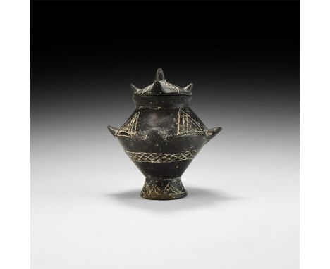 8th-3rd century BC. A ceramic blackware lidded jar comprising a biconvex body with flared neck and four flared lugs to the eq