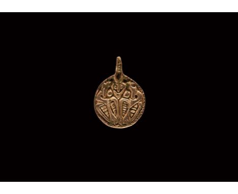 9th-10th century AD. A silver-gilt discoid pendant with integral loop, pelletted border enclosing a low-relief image of a mal