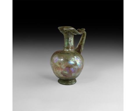 1st century AD. A substantial aqua glass pitcher or jug with slightly eccentric bulbous body, flared base, broad neck with ap