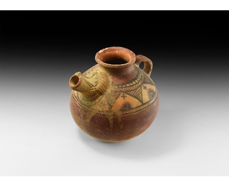 2nd-1st millennium BC. A ceramic vessel with bulbous body and strap handle, applied finely-detailed spout depicting a stylise
