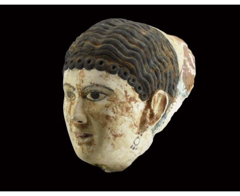 Roman Period, 30 BC-323 AD. A female gesso face mask with wavy hair and a fringe of curls, applied black pigment detailing to