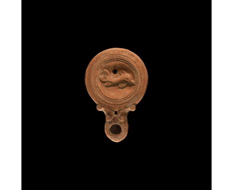 2nd century AD. A ceramic oil lamp with rounded long nozzle, volute scroll to each side, deep discus with concentric circles,