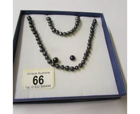 A black pearl necklace, bracelet and earrings.