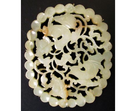 A jade oval white metal mounted as a brooch, the dished pearl border band enclosing two birds pierced and carved amongst flow