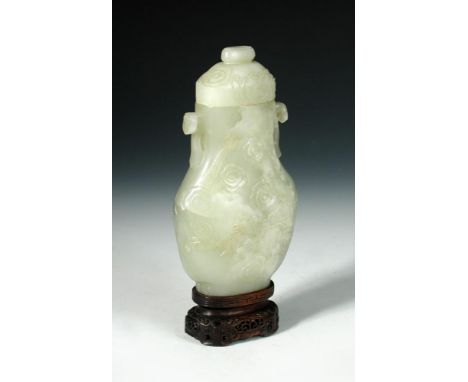 A 20th century nephrite jade vase and cover, the flattened baluster shape carved in relief with dragons amongst clouds, the h