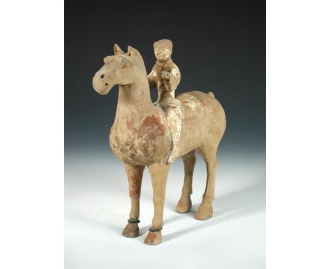 A Han dynasty horse and rider, the figure decorated with traces of white slip holding the horse's head up with reins once in 