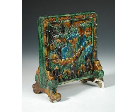 A Ming pottery miniature table screen glazed in green, aubergine, ochre and turquoise with figures on clouds above others out