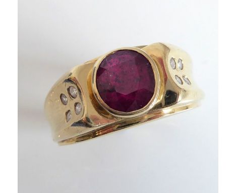 A gentleman's large 9-carat gold ring centrally set with a hand-cut red stone (probably a ruby) and each shoulder flanked by 