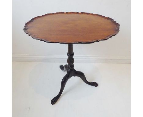 An 18th-century-style mahogany tilt-top wine table; the pie-crust-edged top above a turned and wrythen carved stem, raised on