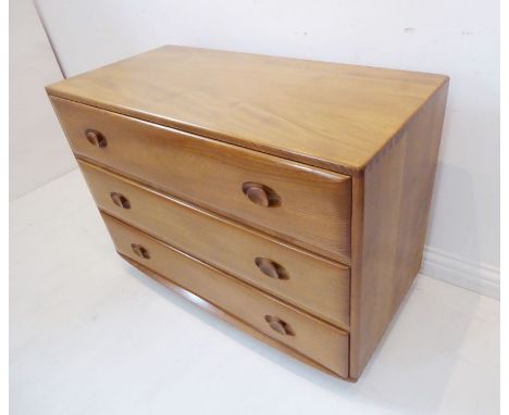 An Ercol (labelled) elm chest of three full-width drawers, raised on castors (91cm wide x 43cm deep x 66cm high)Appears in go