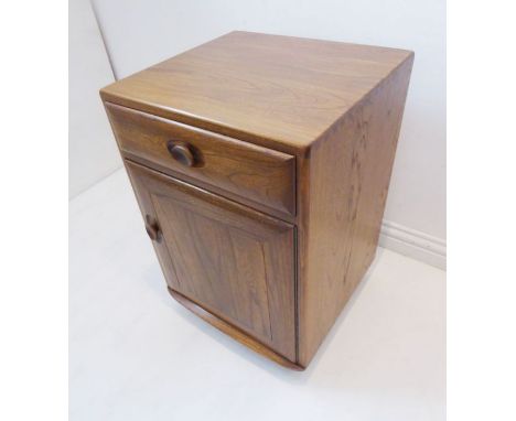 An Ercol (labelled) elm bedside-style cabinet, single full-width drawer above a panelled cupboard door below, raised on reces